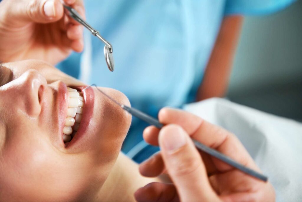 person smiling with dentist holding tools near mouth