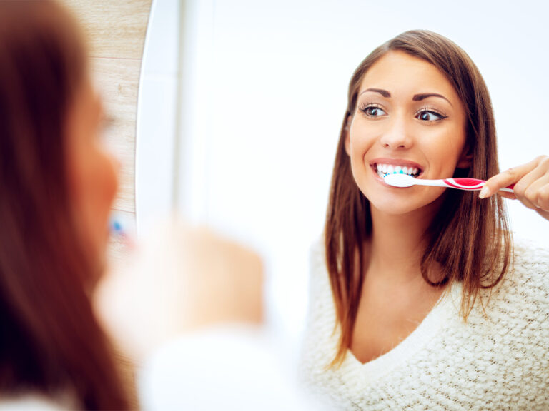 A woman brushing her teeth in the mirror