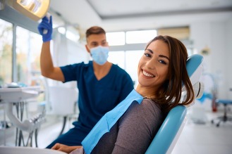 Palos Heights Family Dental exam room showing dentist in blue scrubs preparing for a patient’s checkup under bright natural light.